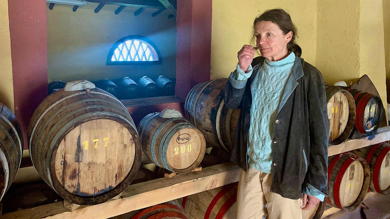 Winemaker Benedetta Contini Bonacossi sniffing a sample of Capezzana Vin Santo from a small wood cask